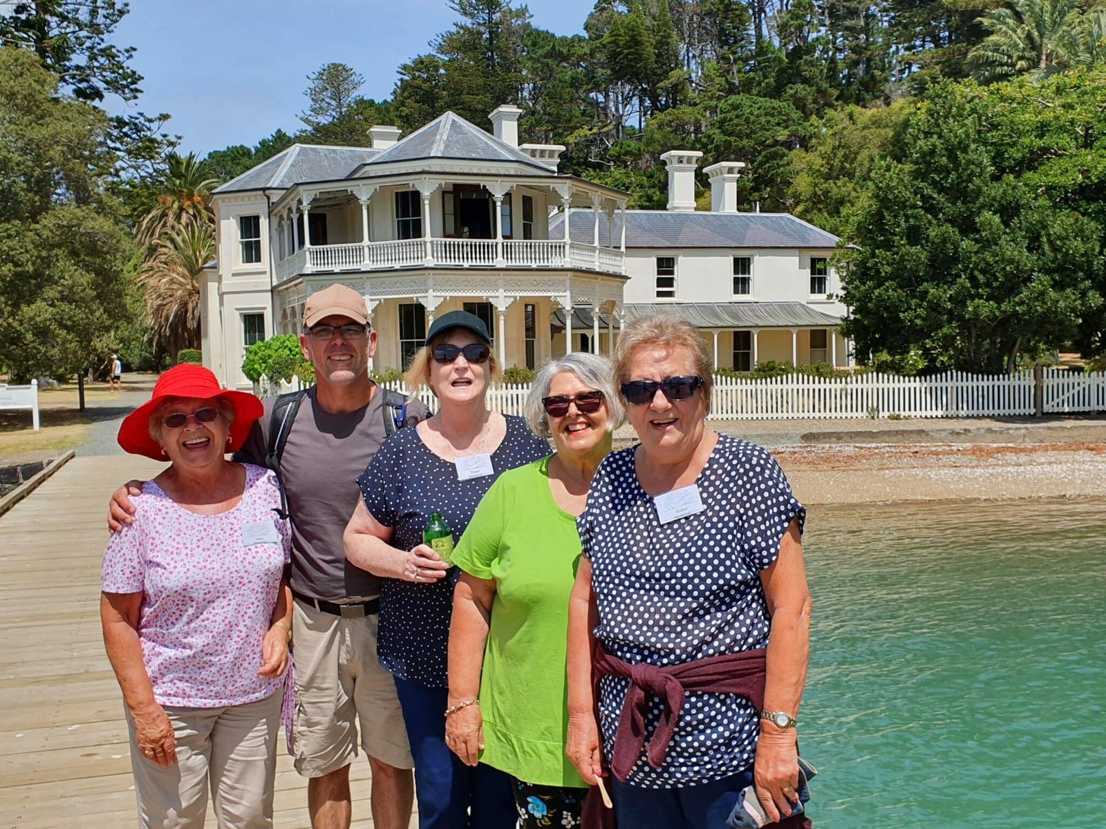 A smiling Silver Rose group on a waterfront boardwalk in front of a historic homestead