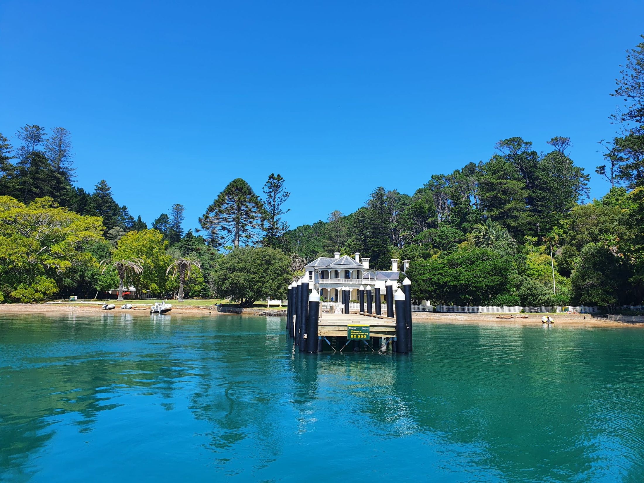 The historic Mansion House and wharf at Mansion House Bay, Kawau Island, across calm turquoise water