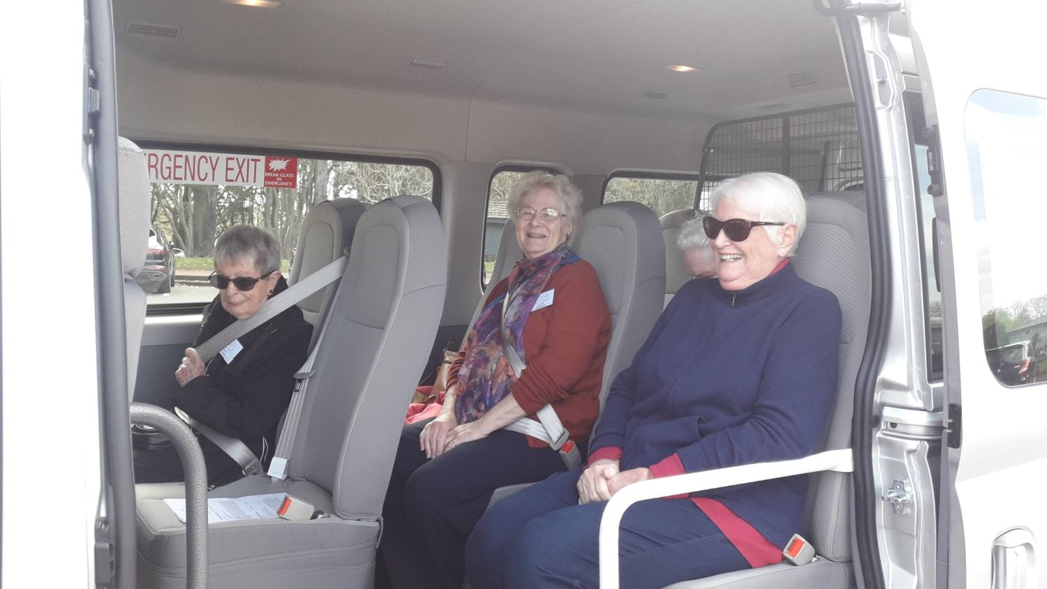 Guests seated comfortably inside the van, with a handrail by the door